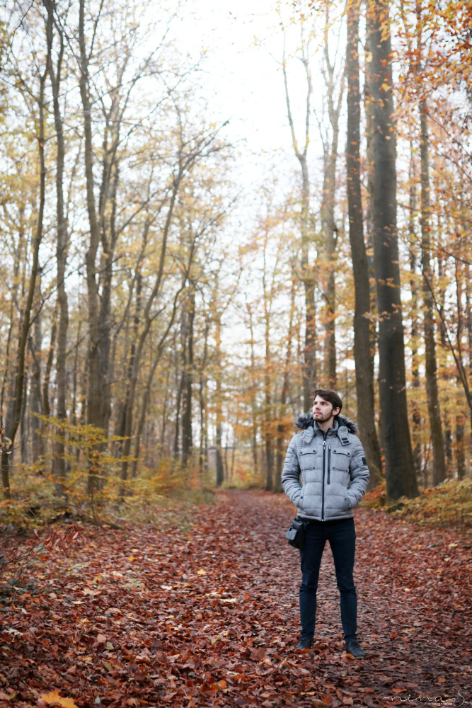 Ein Mann steht auf einem Waldweg und blickt nach oben.